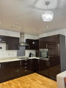 una cocina con armarios de madera oscura y una lámpara de araña en Luxury Lakeview Apartment, en Dartford