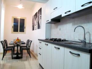 uma cozinha com um lavatório e uma mesa com cadeiras em Trinacria House - Appartamento Deluxe Comiso em Comiso