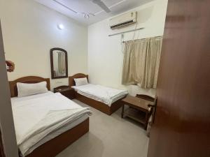 Habitación pequeña con 2 camas y espejo. en Lucky Guest House Bodhgaya, en Bodh Gaya