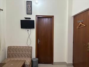 Habitación con puerta, silla y TV. en Lucky Guest House Bodhgaya, en Bodh Gaya