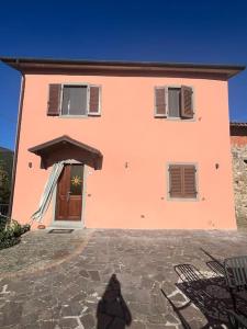 a person standing in front of a pink house at Casa Berton in Mochignano