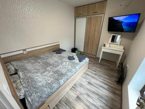 Schlafzimmer mit einem Bett, einem Schreibtisch und einem TV in der Unterkunft Апартамент Божур in Warna