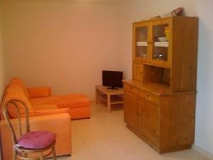 ein Wohnzimmer mit einem orangenen Sofa und einem Schrank in der Unterkunft Ferienwohnung für 6 Personen ca 75 m in Pellizzano, Trentino Val di Sole in Trient