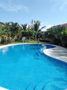 a large blue swimming pool with palm trees in the background at BEAUTIFUL HOME FULLY FURNISHED, READY TO RELAX AND 5 MINUTES FROM THE BEACH!! in Ixtapa