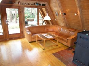um sofá de couro numa sala de estar com uma mesa em Nurdachferienhaus in ruhiger Lage, auf einem naturbelassenem Grundstück mit nahegelegener Angelmöglichkeit - b48731 em Wienhausen