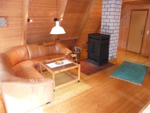 uma sala de estar com um sofá de couro e um fogão em Nurdachferienhaus in ruhiger Lage, auf einem naturbelassenem Grundstück mit nahegelegener Angelmöglichkeit - b48731 em Wienhausen