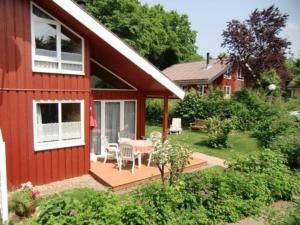 a red house with a deck and a table and chairs at Ferienhaus Mia im Ferienpark Extertal zwischen Teutoburger Wald und Weserbergland, Natur in Extertal +13 photos