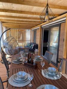 una terraza de madera con una mesa con platos y copas de vino en mobile home MIRNA en Biograd na Moru