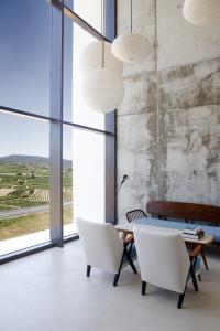 ein Esszimmer mit weißen Stühlen, einem Tisch und großen Fenstern in der Unterkunft Hotel-Bodega Finca de Los Arandinos in Entrena