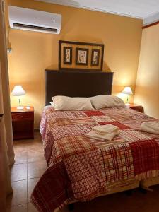 a bedroom with a bed with a red blanket and two lamps at Cabañas Altos de Artalaz in Colón