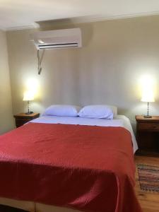 a bedroom with a red bed with two lamps at Cabañas Altos de Artalaz in Colón