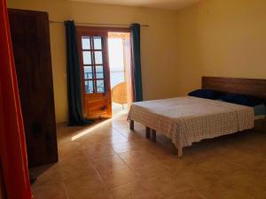 Cidade VelhaにあるGet house kiraのベッドルーム1室(ベッド1台付)、窓、ドアが備わります。