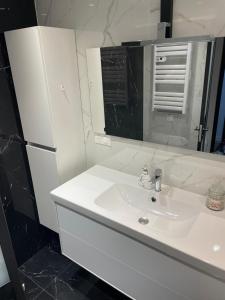 a white bathroom with a sink and a refrigerator at Appartement 3 pieces 2 minutes à pied RER vers Paris in Gagny