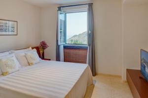 ein Schlafzimmer mit einem großen Bett mit einem großen Fenster in der Unterkunft Villa Belvedere by Il Leccio Luxury Resort in Santa Margherita Ligure