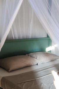 1 cama con cabecero verde y dosel blanco en Beachbums CoLiving Midigama, en Midigama East