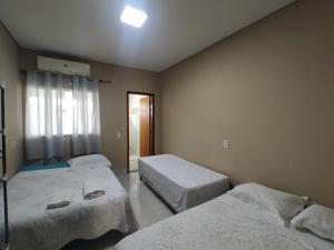a room with two beds and a window in it at Churrasqueira e Casa privativa, Acesse os 2 quartos com 2 ar e banheiros se reservar 4 ou mais hóspedes, até 6 camas e tem pátio, roupa de cama, portão eletrônico e Desconta duração! Entrada padrão 15h adiante, inclusive à noite - Projeto Suíte Sorriso in Sorriso