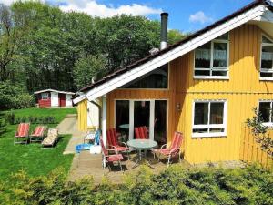 una casa amarilla con sillas y una mesa al aire libre en Gemütliches Ferienhaus Alissa für 5 Personen mit Sauna und Kaminofen von Privat im Ferienpark Extert, en Extertal