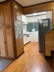 a kitchen with a stainless steel refrigerator and wooden floors at 海が見ながらBBQできる宿/カラオケ/美ら海水族館車で５分/最大１２名/ in Jahana