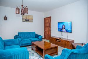 ein Wohnzimmer mit blauen Sofas und einem Flachbild-TV in der Unterkunft Kilimani Extended Stays in Nairobi