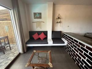 a room with a bench with red pillows on it at Departamento con vista al mar y piscina compartida in Máncora