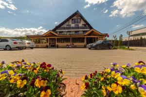 a building with cars parked in a parking lot with flowers at Pensiunea Koronka in Corunca