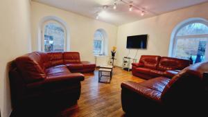 uma sala de estar com mobiliário de couro e uma televisão de ecrã plano em Maison de maître & spa em Cornimont