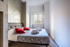 a bedroom with a bed with red pillows and a window at Portside Aparthotel in Rome