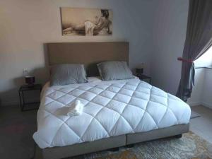 een groot wit bed met een witte knuffel erop bij Appartamento confortevole in Deinze