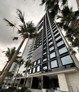 um edifício alto com palmeiras em frente em La comodidad de un hogar na Cidade do Panamá
