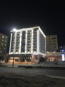 a large white building with lights on it at night at فندق وشقق ليالي الاحلام للشقق المخدومه in Baljurashi