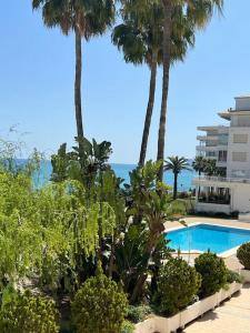 een zwembad met palmbomen en de oceaan bij Zee zicht apartement Altea 2 pers in Caserío Capnegret