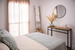 1 dormitorio con cama, espejo y ventana en Ramos Gardens, en Baena