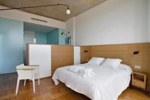 una camera con un grande letto bianco e una sedia di Hotel-Bodega Finca de Los Arandinos a Entrena