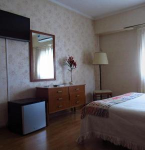 - une chambre avec un lit, une commode et un miroir dans l'établissement Hotel Perugia, à Necochea