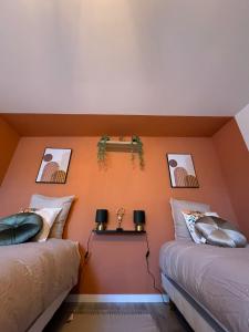 2 łóżka w pokoju z pomarańczowymi ścianami w obiekcie La maison de LYA (lyaroom) 
