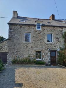 a stone house with a driveway in front of it at Charmante maison en bord de Rance in Plouër-sur-Rance