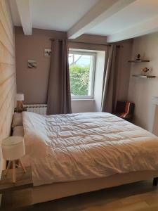 a bedroom with a large bed and a window at Charmante maison en bord de Rance in Plouër-sur-Rance