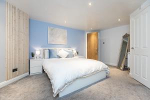 een slaapkamer met een wit bed en een blauwe muur bij Garden Apartment - Close to Town Centre - sleeps 6 in Buxton