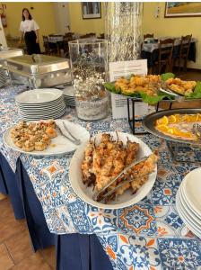 einen Tisch mit Teller mit Speisen darüber in der Unterkunft C.R.D.D. Due Torri Riccione in Riccione