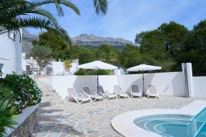 - un groupe de chaises longues et de parasols à côté de la piscine dans l'établissement Villa with spectacular vieuw and swimmingpool., à Altea