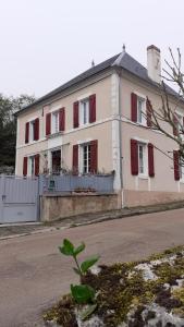 ein weißes Haus mit roten Rollläden auf einer Straße in der Unterkunft Gite des Belles Fontaines in Druyes-les-Belles-Fontaines