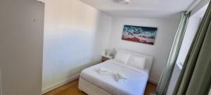 ein weißes Zimmer mit einem Bett und einem Gemälde an der Wand in der Unterkunft Relax and Explore Lisbon Suites and Rooms in Lissabon