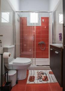 a bathroom with a toilet and a shower with red tiles at Pearl of Stegna - Beach House in Archangelos