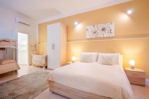 una camera da letto con un grande letto bianco e pareti gialle di Montellino's Suite Oro a SantʼAntìoco
