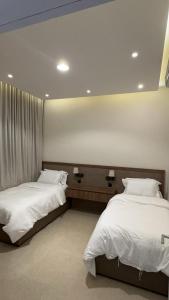2 bedden in een kamer met witte lakens bij شقق السيف الفندقية in Riyad