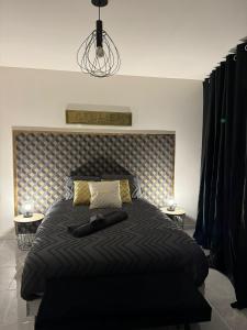 a bed with a black comforter and two tables at La maison de LYA (lyaroom) 