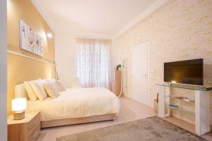 a bedroom with a bed and a flat screen tv at Montellino's Suite Oro in SantʼAntìoco