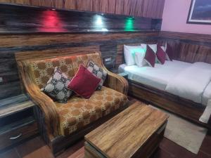 a room with two beds and a chair and a bench at Express Myagdi Hotel Pvt Ltd in Kathmandu