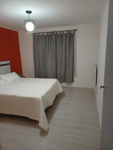 1 dormitorio con cama blanca y ventana en Casa Catalina zona sur en Comodoro Rivadavia