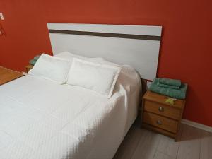 1 dormitorio con cama blanca y pared de color naranja en Casa Catalina zona sur en Comodoro Rivadavia